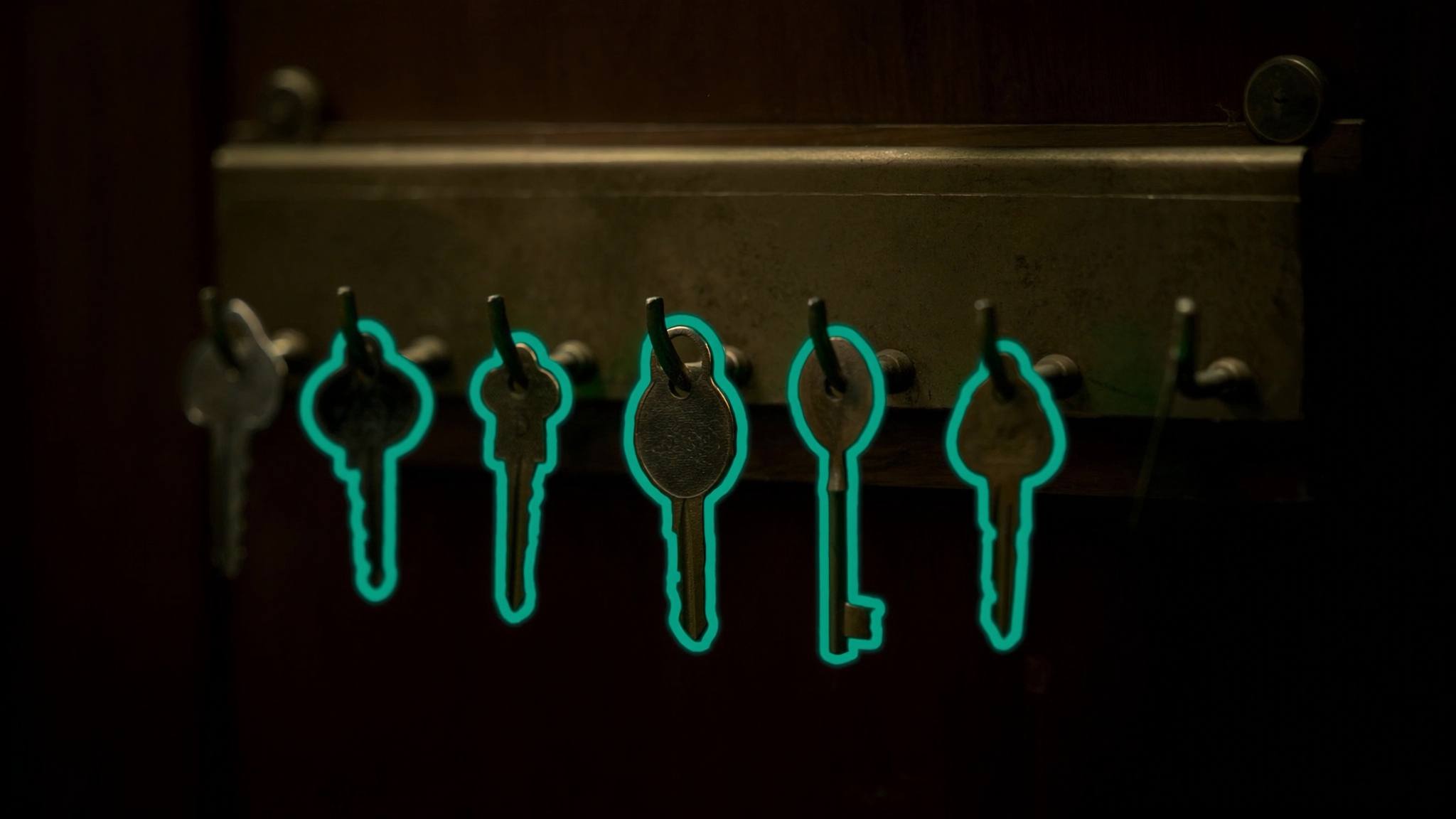 Messing-Schlüsselbrett an dunkler Wand, ein Haken leer, teal leuchtende Umrisse