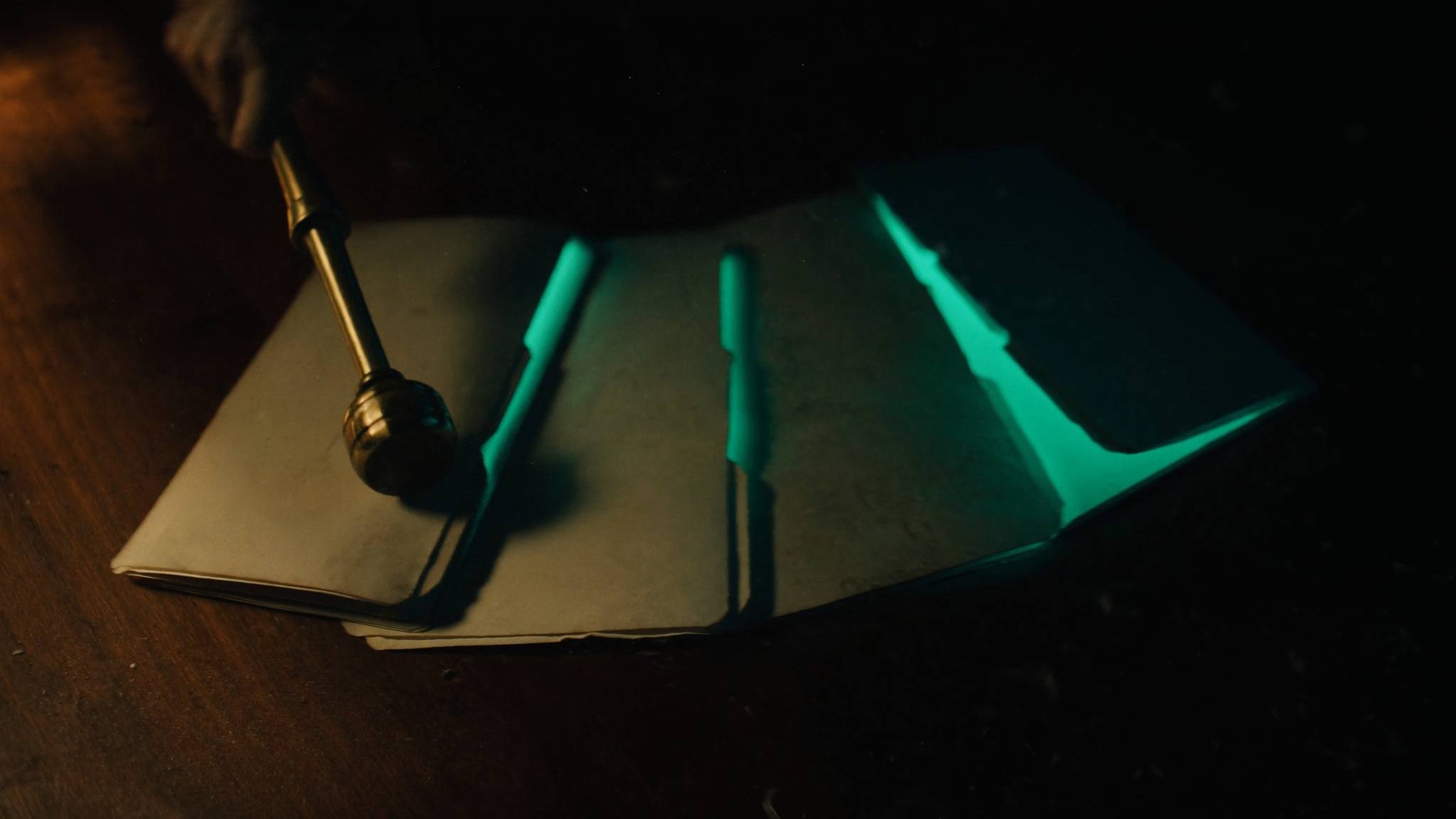 Vier alte Aktendeckel auf dunklem Holz, aus jedem dringt teal leuchtendes Licht