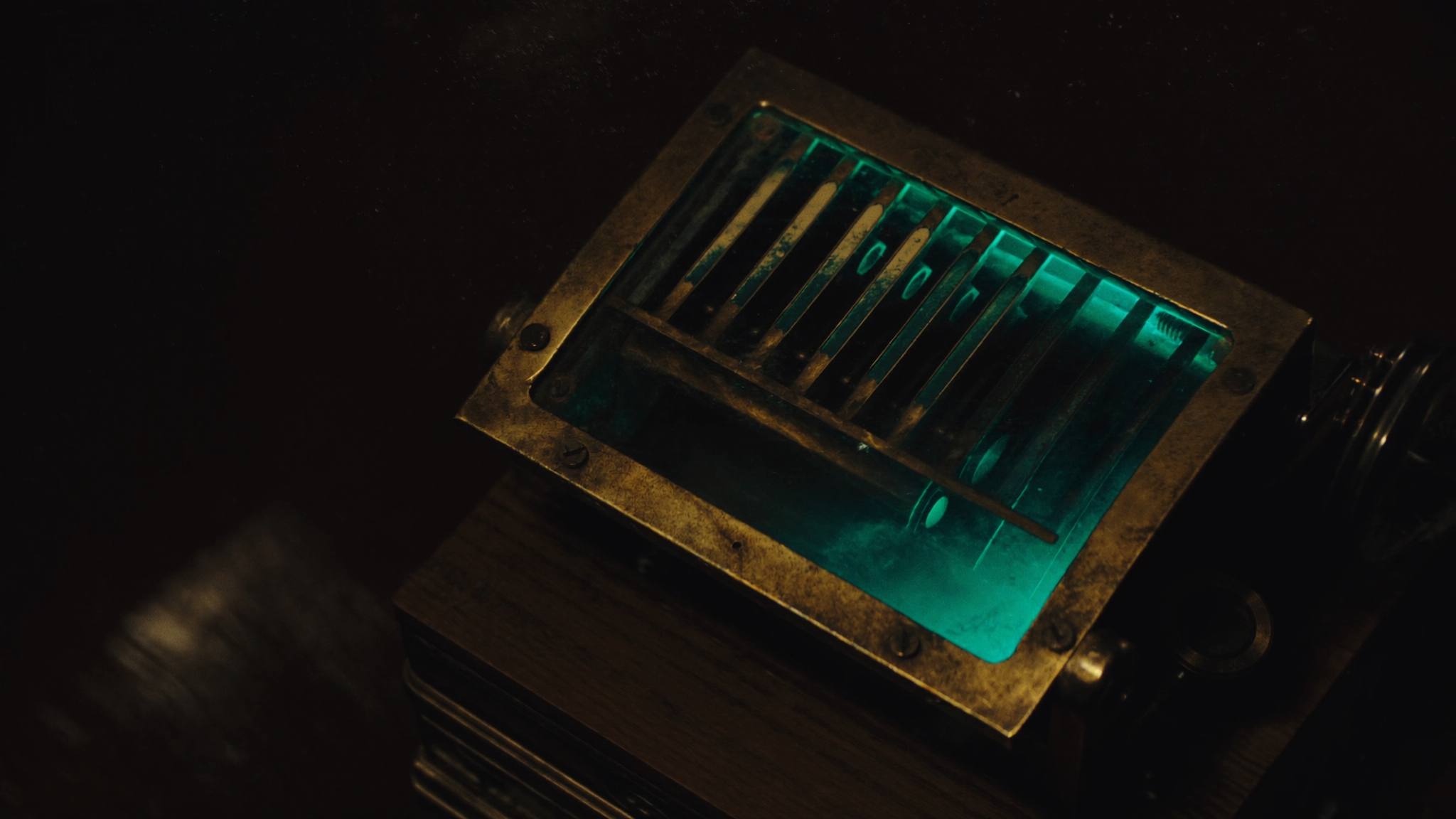 Alte Messing-Rechenmaschine auf dunklem Holz, teal leuchtendes Zählwerk