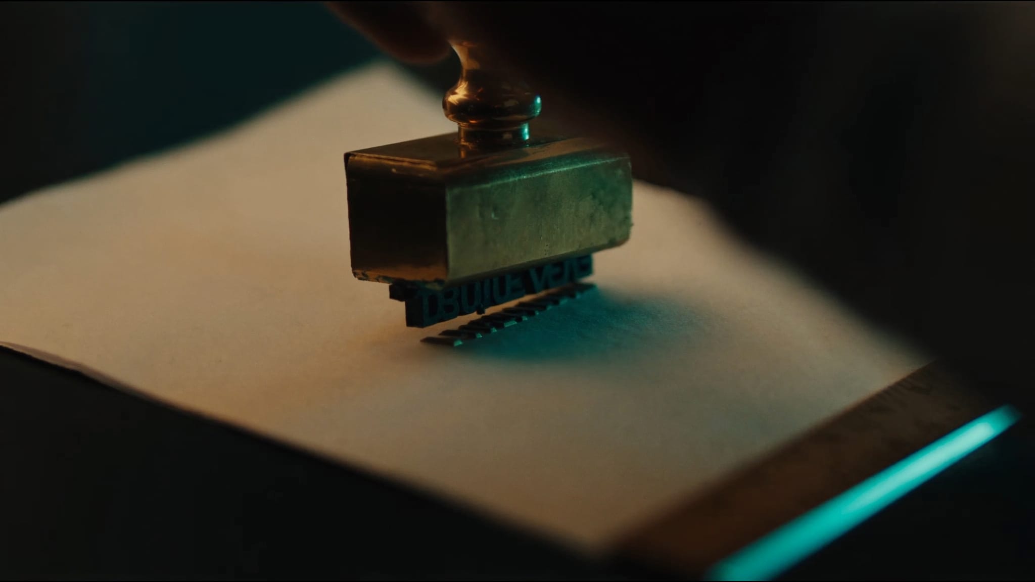 Ein Messing-Stempel drückt ein einzelnes Wort auf cremefarbenes Papier