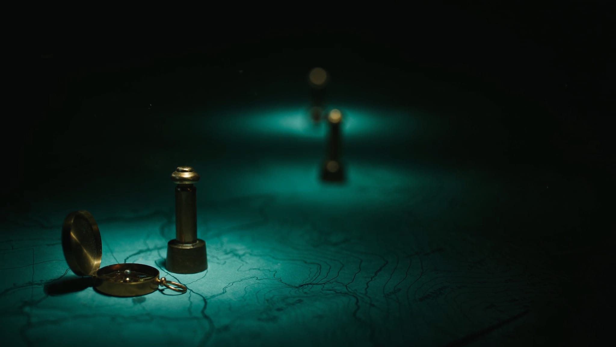 Vier Messing-Vermessungsmarken entlang eines Teal-Pfades, ein Kompass daneben