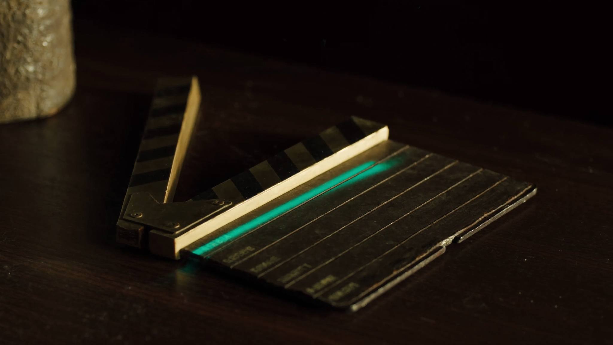 Alte Filmklappe aus Messing auf dunklem Holz, teal leuchtende Markierungen